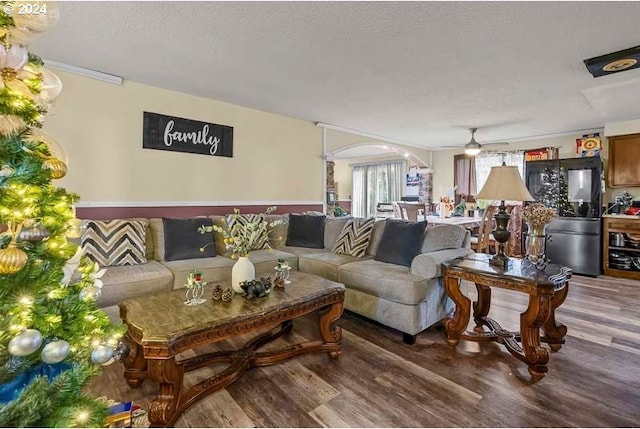 living room featuring ceiling fan, ornamental molding, a textured ceiling, and hardwood / wood-style flooring