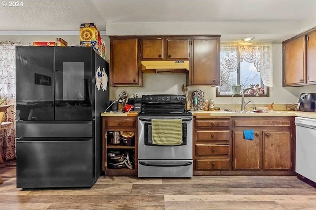 kitchen with black refrigerator, light wood-type flooring, dishwasher, and stainless steel electric range