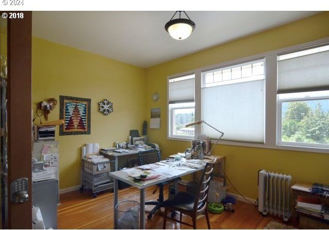 office area with hardwood / wood-style flooring, plenty of natural light, and radiator