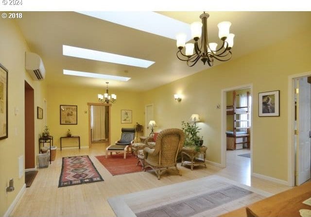 living room featuring a wall mounted air conditioner, a chandelier, light hardwood / wood-style floors, and a skylight