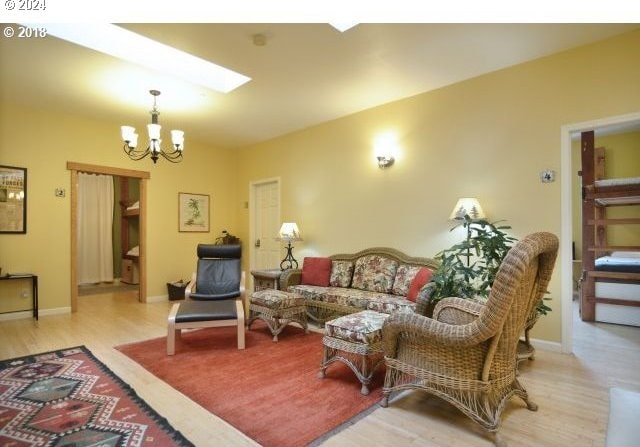 living room with a skylight, light hardwood / wood-style flooring, and a chandelier