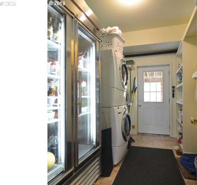 laundry area featuring stacked washer and dryer and light tile patterned floors