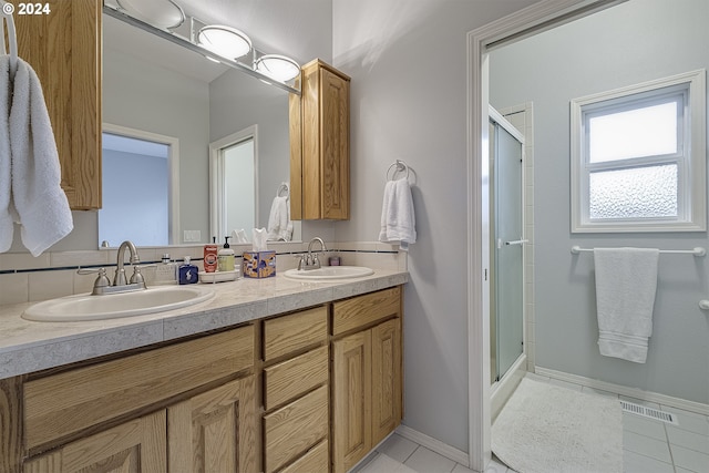 bathroom with tile patterned flooring, double sink vanity, and a shower with door