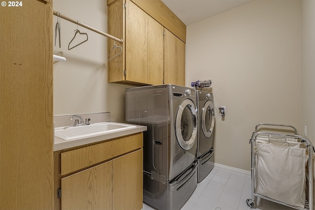 clothes washing area featuring light tile patterned floors, sink, separate washer and dryer, and cabinets