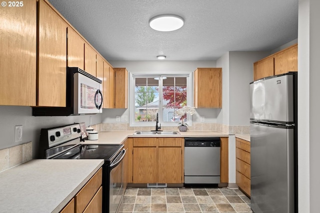 342 NW Denton Ave, Dallas, OR 97338 - kitchen with appliances with stainless steel finishes, a sink, light countertops, a textured ceiling, and stone finish floors