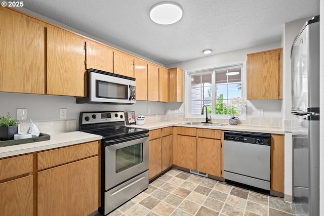 342 NW Denton Ave, Dallas, OR 97338 - kitchen featuring appliances with stainless steel finishes, a sink, light countertops, a textured ceiling, and stone finish floors