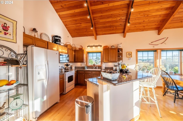 kitchen featuring lofted ceiling with beams, dark stone countertops, a kitchen bar, wooden ceiling, and white appliances