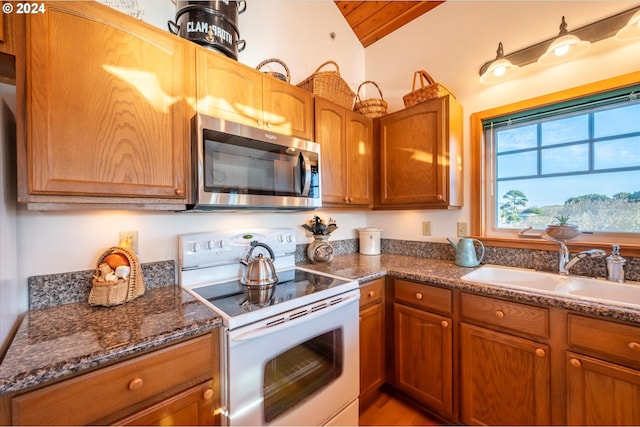 kitchen featuring dark stone countertops, sink, vaulted ceiling, and white range with electric stovetop