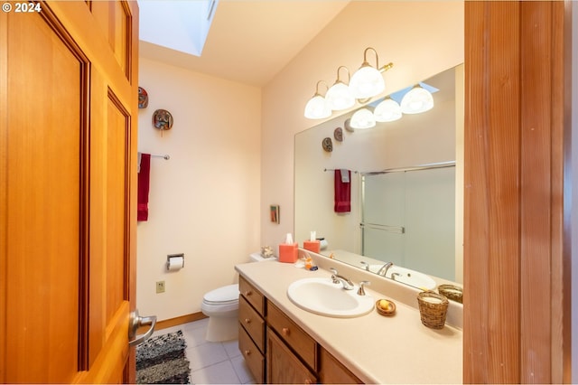 bathroom with a skylight, tile patterned flooring, vanity, an enclosed shower, and toilet