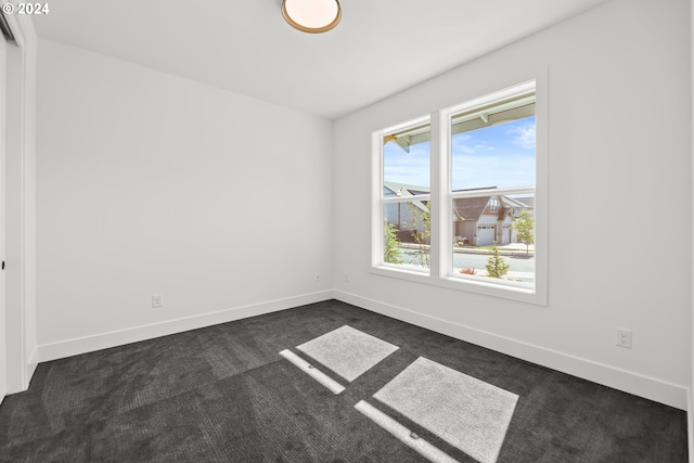 spare room featuring dark colored carpet