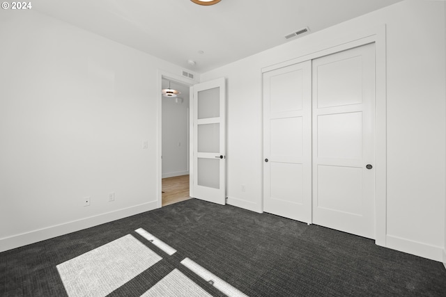 unfurnished bedroom with a closet, dark colored carpet, and french doors