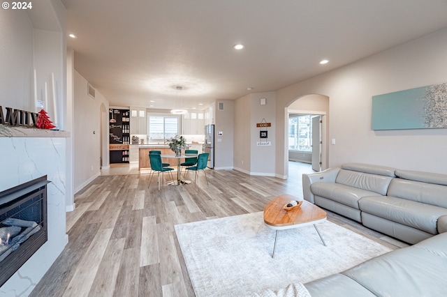 living room with a high end fireplace, light wood-type flooring, and heating unit