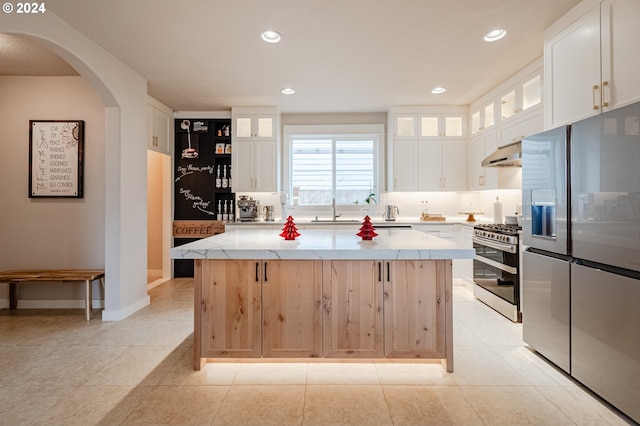 kitchen with white cabinetry, a kitchen island, light tile patterned floors, and appliances with stainless steel finishes