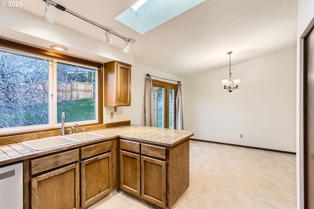 kitchen with pendant lighting, stainless steel dishwasher, kitchen peninsula, and tile counters