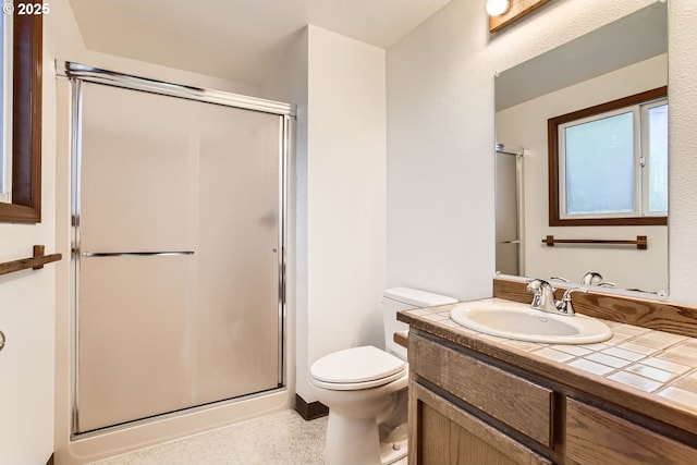 bathroom featuring a shower with door, vanity, and toilet