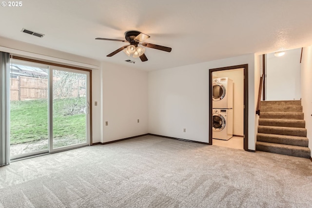 interior space featuring stacked washing maching and dryer, light colored carpet, and ceiling fan