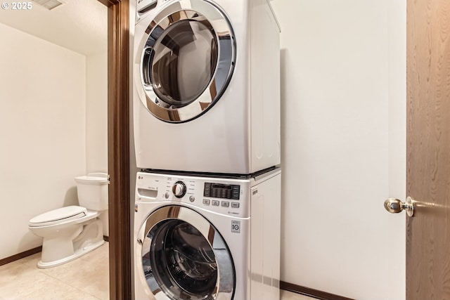 clothes washing area featuring light tile patterned flooring and stacked washer / dryer