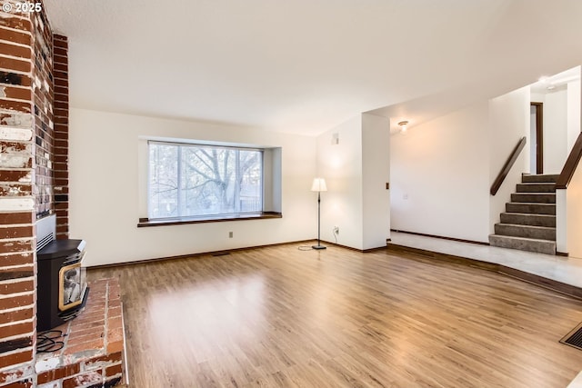 unfurnished living room with a wood stove and hardwood / wood-style flooring