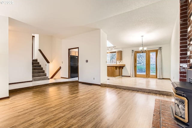 unfurnished living room with a textured ceiling, a chandelier, and wood-type flooring