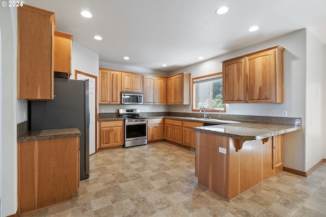 kitchen with a breakfast bar, stainless steel appliances, sink, and kitchen peninsula