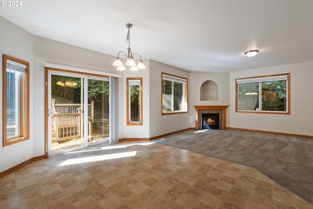 unfurnished living room featuring light colored carpet, an inviting chandelier, and a healthy amount of sunlight