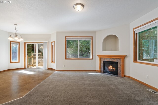 unfurnished living room with a tiled fireplace, an inviting chandelier, and a textured ceiling