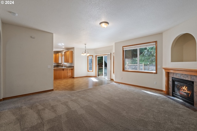 unfurnished living room featuring carpet flooring, a fireplace, a notable chandelier, and a textured ceiling