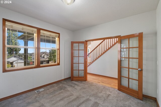 unfurnished room featuring light colored carpet and french doors