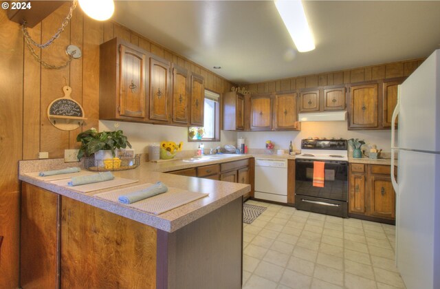 94200 Austin Ct, Gold Beach, OR 97444 - kitchen with light countertops, white appliances, under cabinet range hood, a peninsula, and brown cabinets