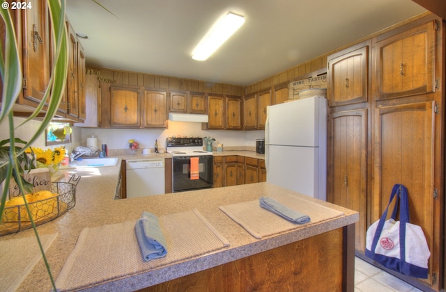 94200 Austin Ct, Gold Beach, OR 97444 - kitchen with light countertops, a sink, a peninsula, under cabinet range hood, and white appliances