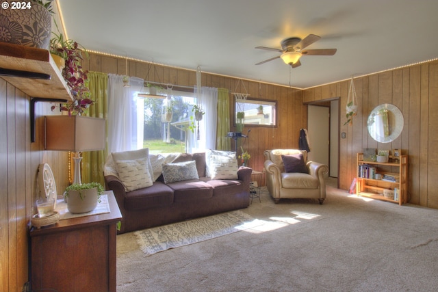 carpeted living room featuring ceiling fan and wooden walls