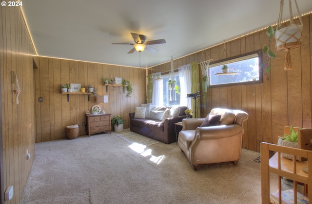 carpeted living room featuring wooden walls and ceiling fan