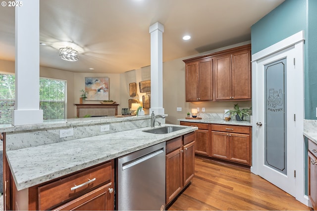 kitchen with ornate columns, light stone countertops, dishwasher, sink, and light hardwood / wood-style floors