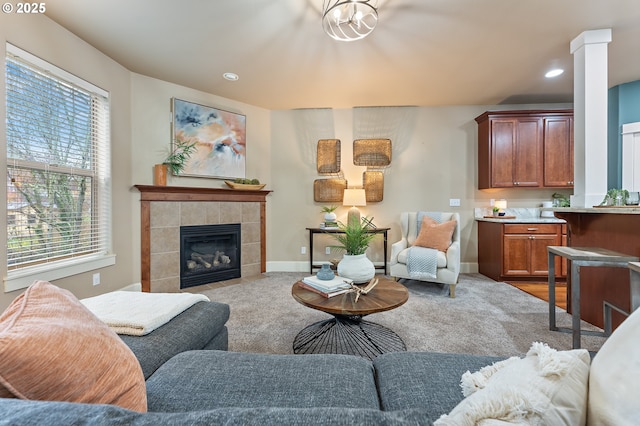 living room with a tile fireplace, ornate columns, and a healthy amount of sunlight