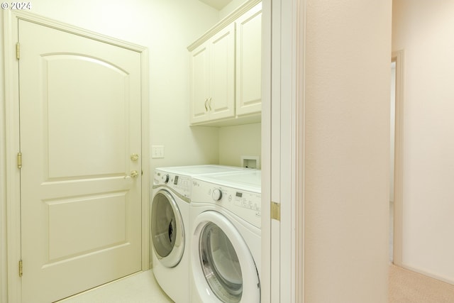 clothes washing area with cabinets and separate washer and dryer