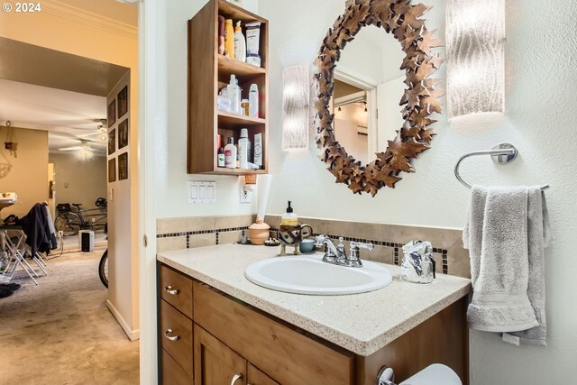 bathroom featuring ceiling fan, crown molding, and vanity