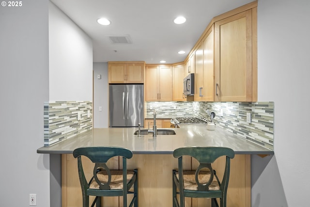 kitchen featuring a kitchen breakfast bar, appliances with stainless steel finishes, sink, and light brown cabinets