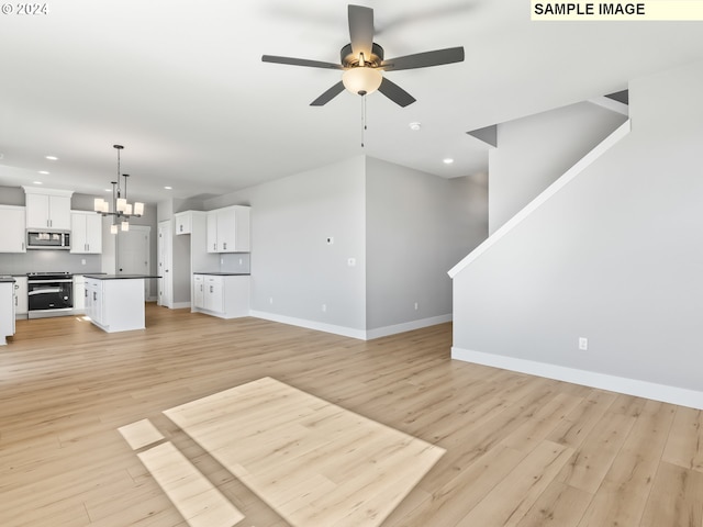 unfurnished living room with ceiling fan with notable chandelier and light hardwood / wood-style floors