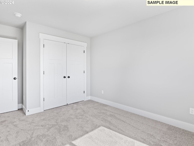 unfurnished bedroom featuring light carpet and a closet