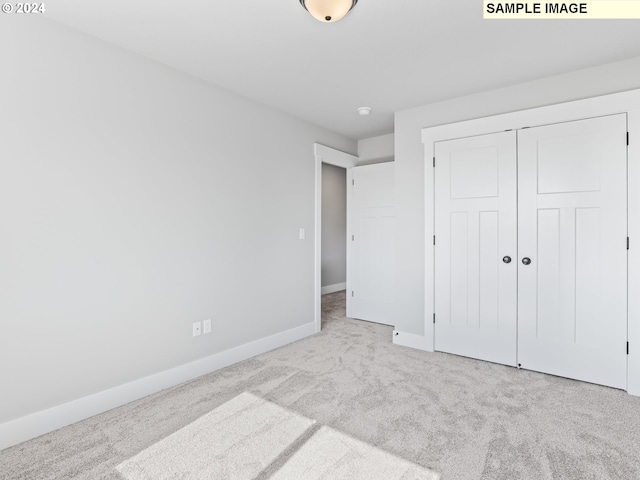 unfurnished bedroom with light colored carpet and a closet