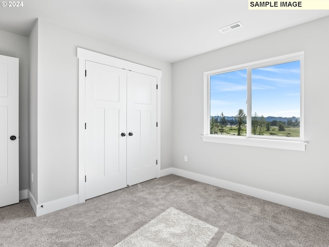 unfurnished bedroom with a closet and light colored carpet