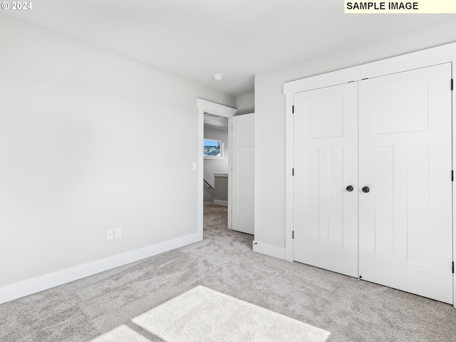 unfurnished bedroom featuring a closet and light colored carpet