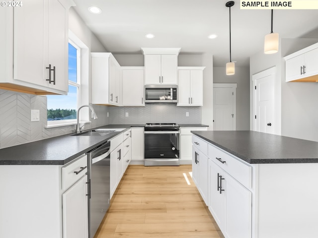 kitchen featuring stainless steel appliances, sink, white cabinets, light hardwood / wood-style floors, and hanging light fixtures