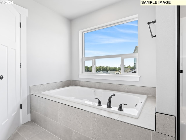 bathroom with tiled bath and tile patterned flooring