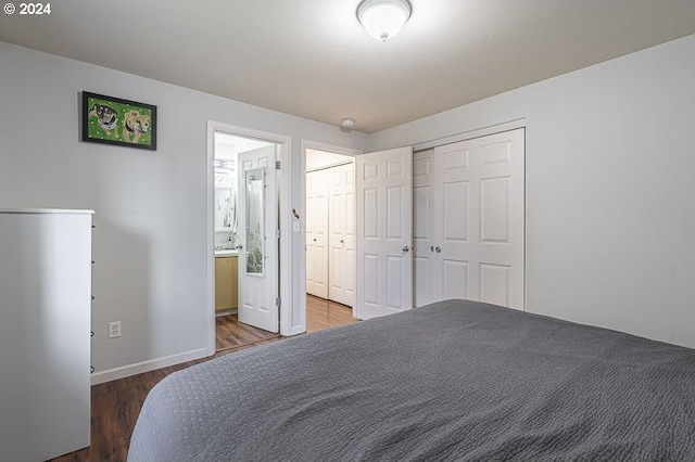 bedroom featuring ensuite bath, multiple closets, and dark wood-type flooring