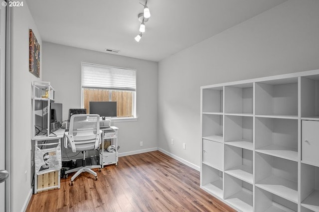 office area with hardwood / wood-style floors and rail lighting