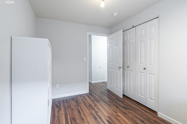 unfurnished bedroom with dark hardwood / wood-style flooring and a closet