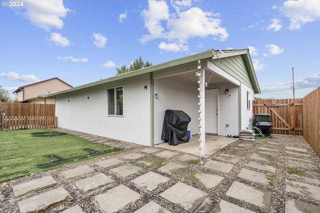 rear view of house with a patio and a lawn