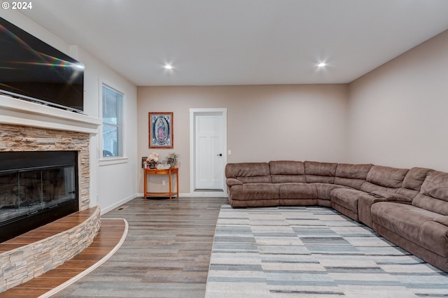 living room with a stone fireplace and light wood-type flooring