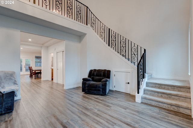 staircase featuring french doors, a towering ceiling, and hardwood / wood-style flooring